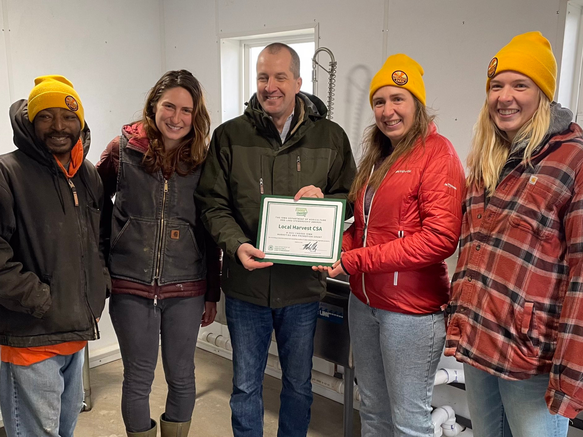 3 women and 2 men stand and pose with a certificate.