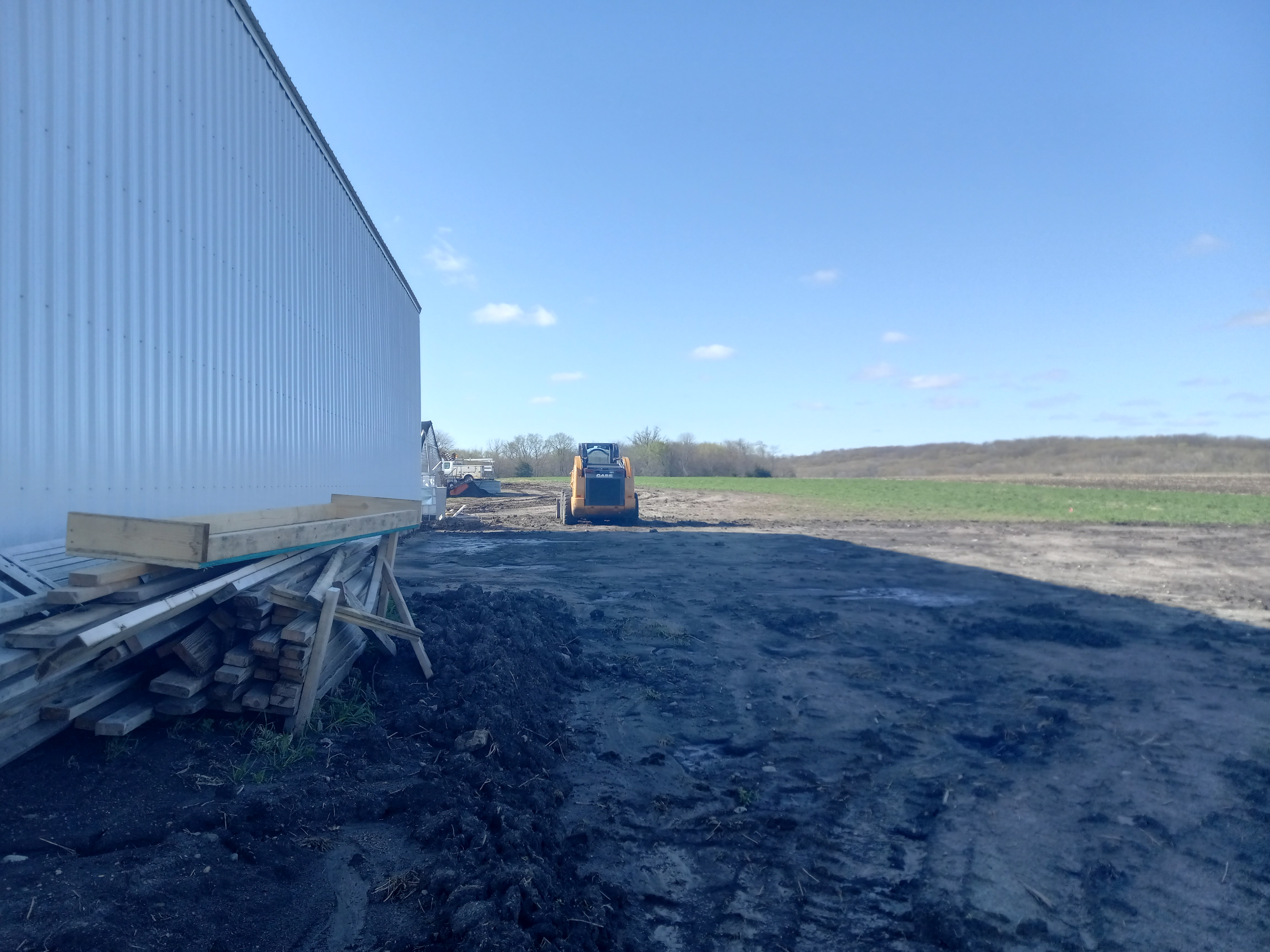 A skid steer sits ready to be used next to a shed.