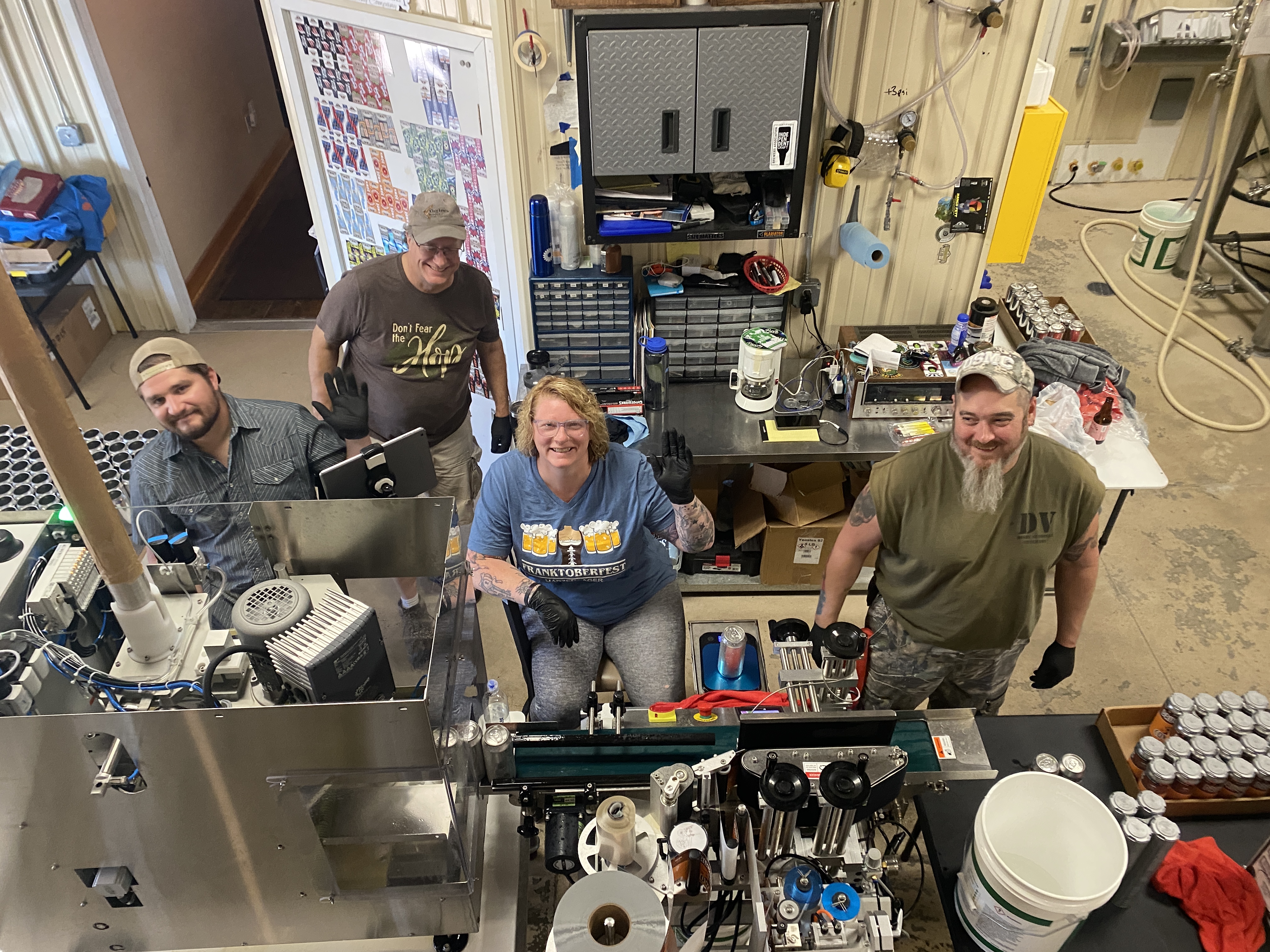 4 folks stand in a brewing room.