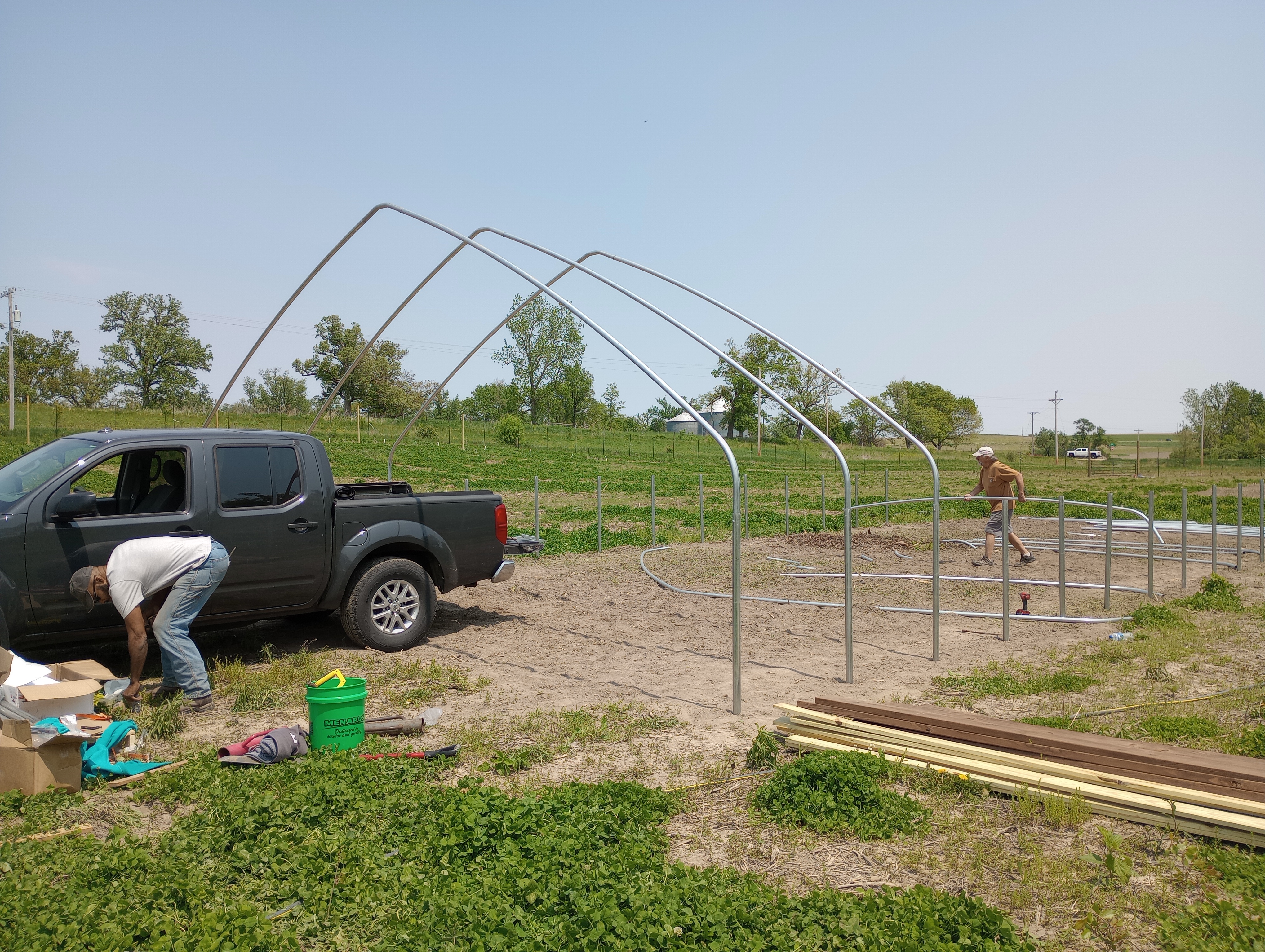 A couple individuals work on construction of a hoop house frame.