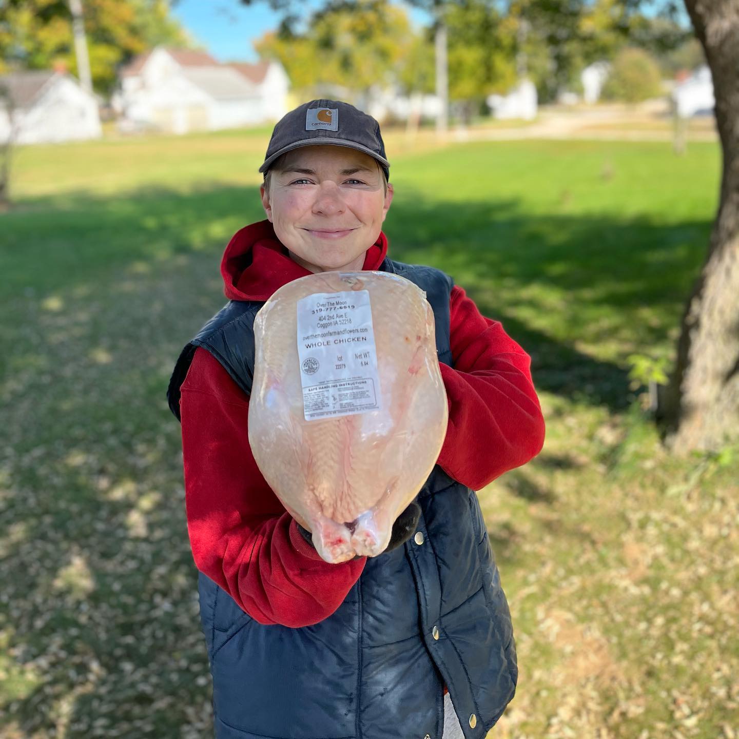 A woman holds a whole chicken carcass ready for cooking.