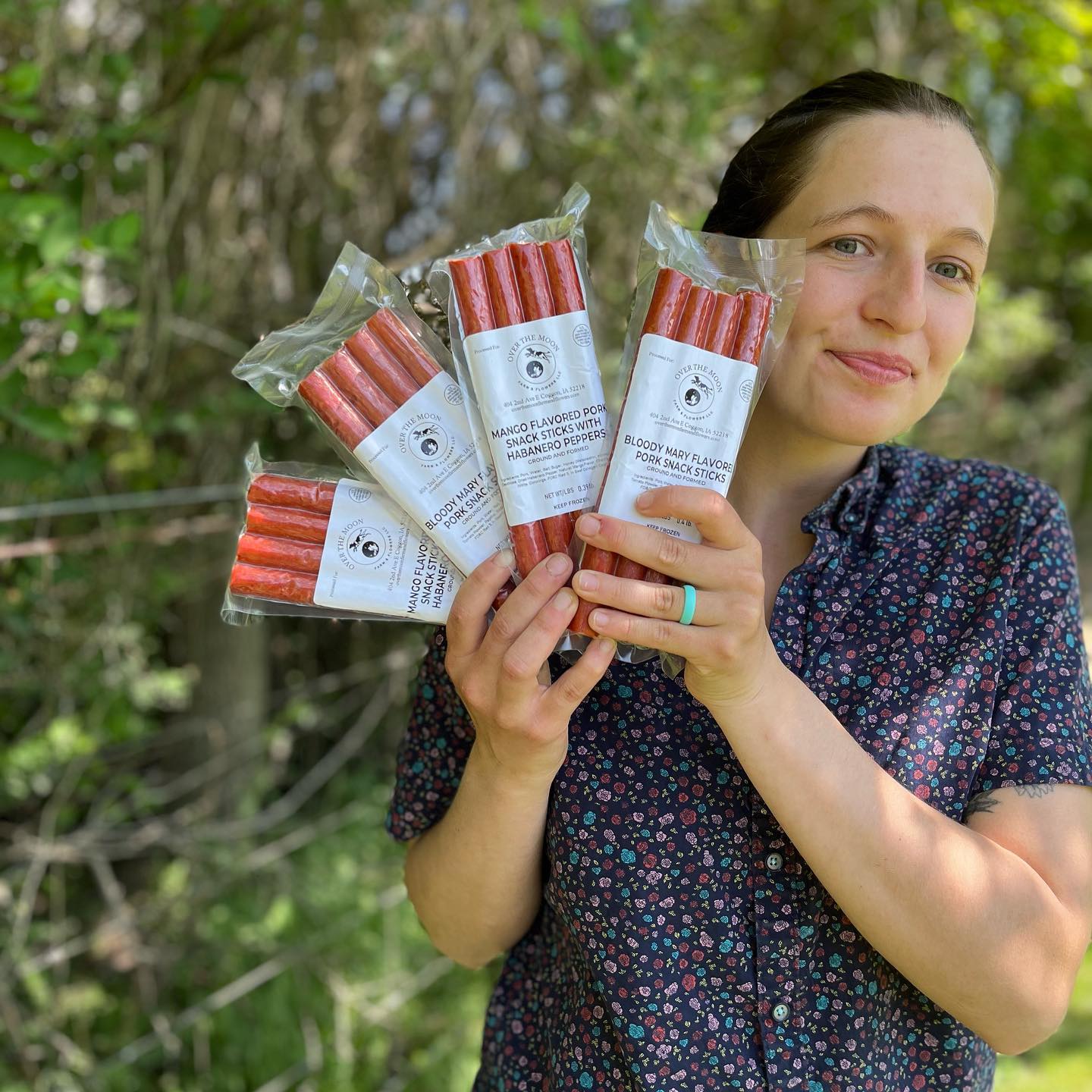 A woman holds several packages of snack sticks in different flavors.