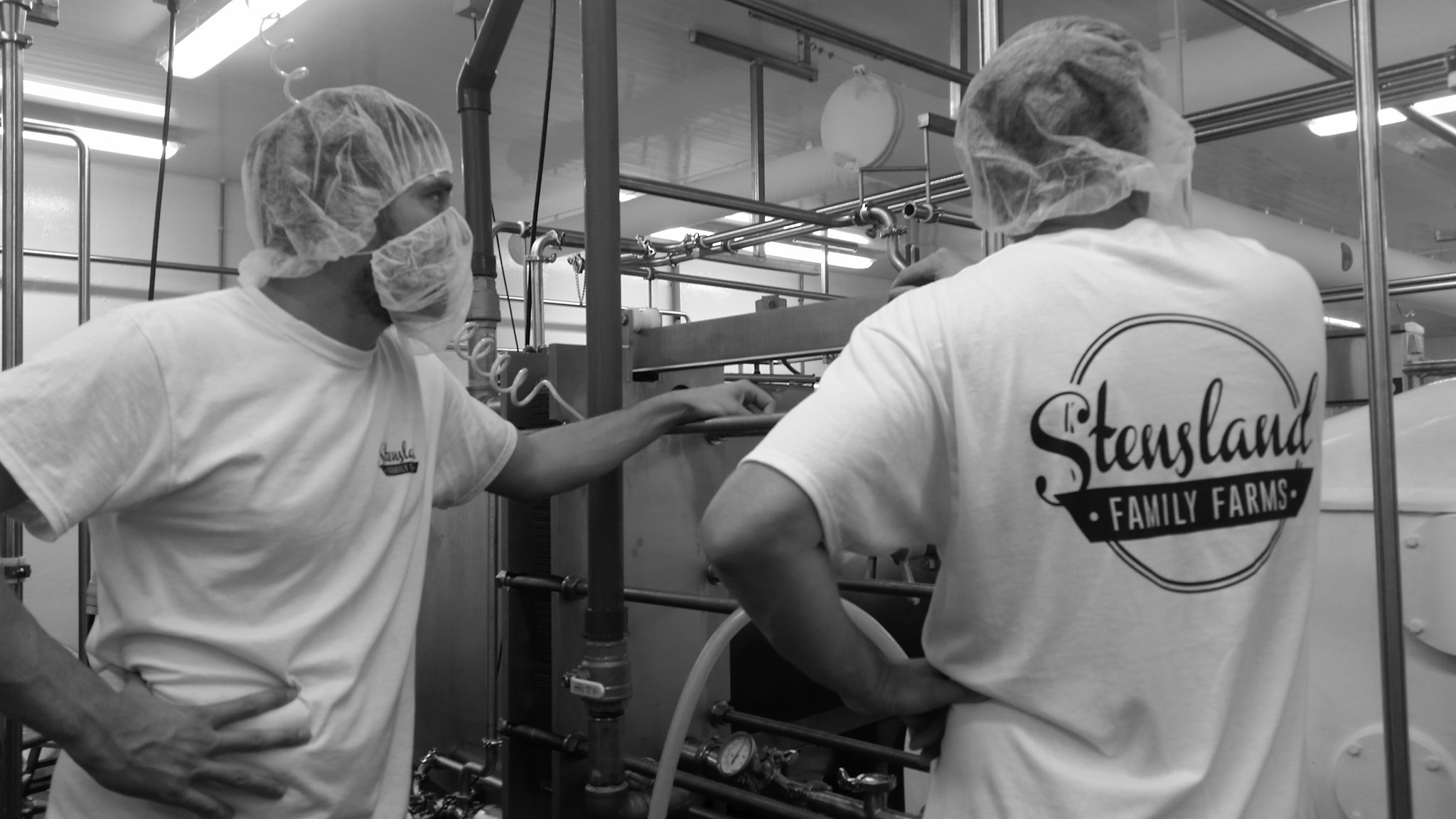 Two men stand new a bunch of ice cream equipment.