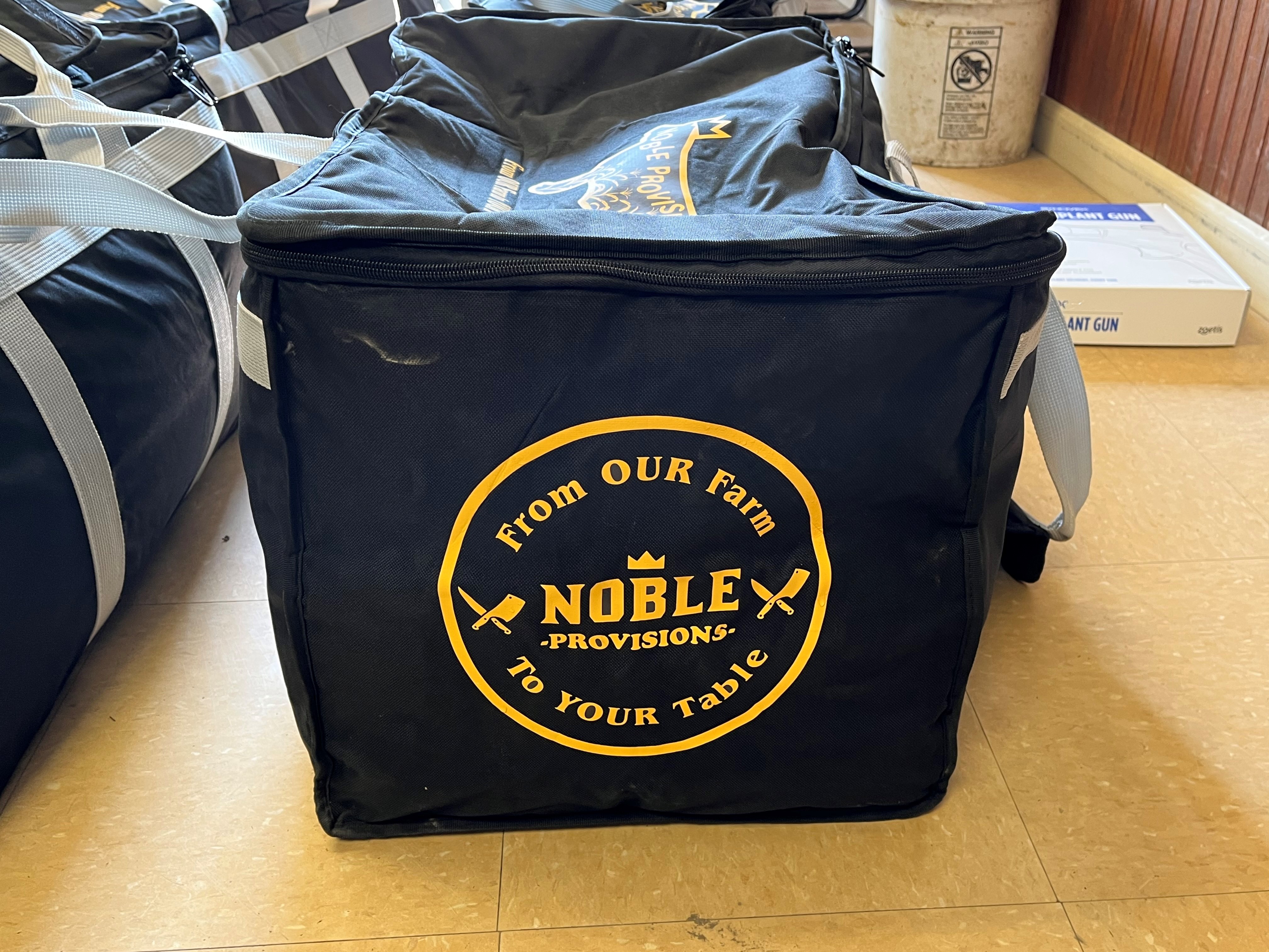 A black insulated bag has the noble provisions logo.