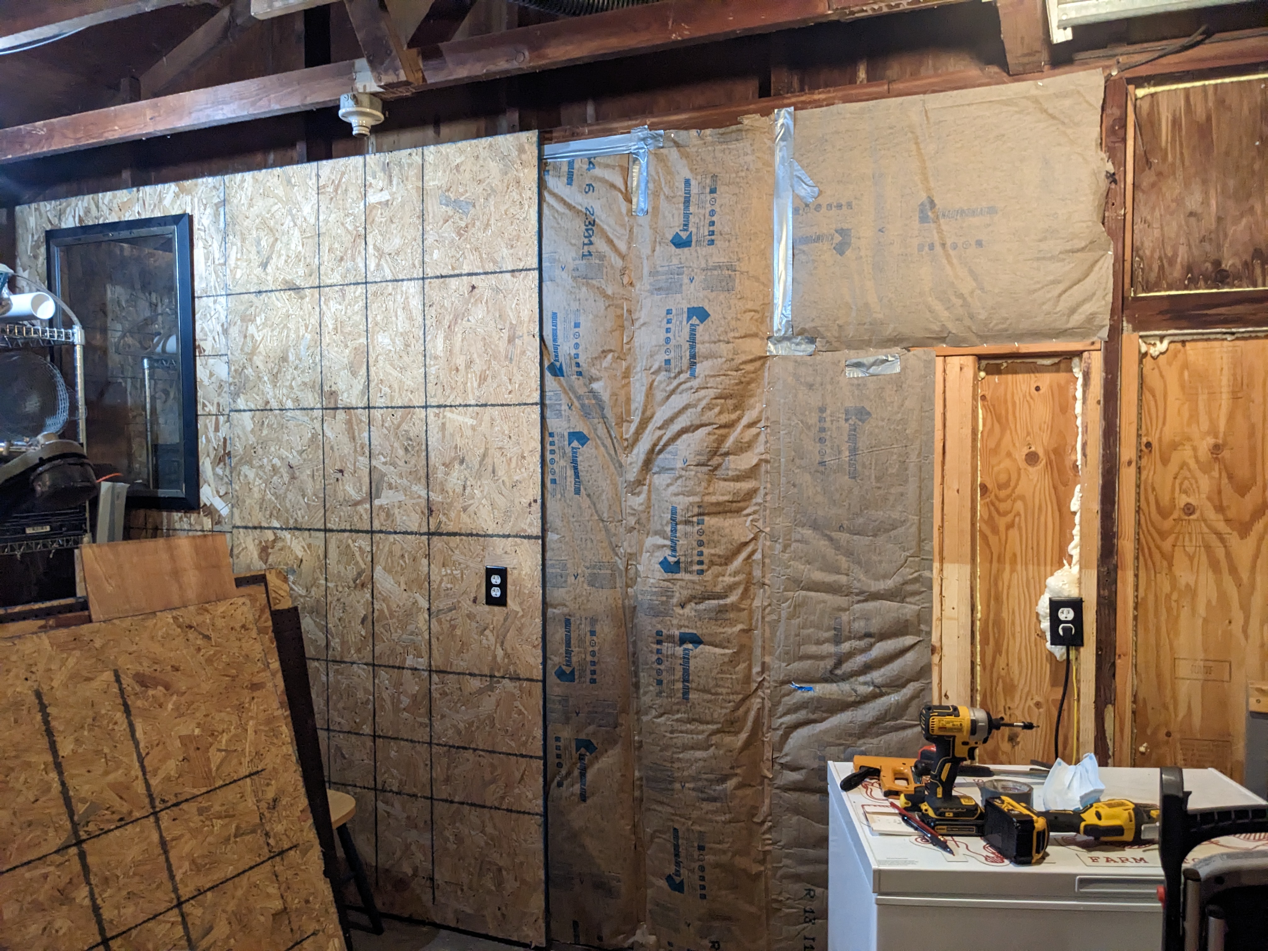 A garage wall is picture that is being insulated and covered with plywood.