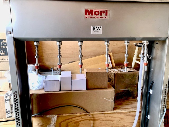 A Mori bottling equipment piece sits in front of many boxes.