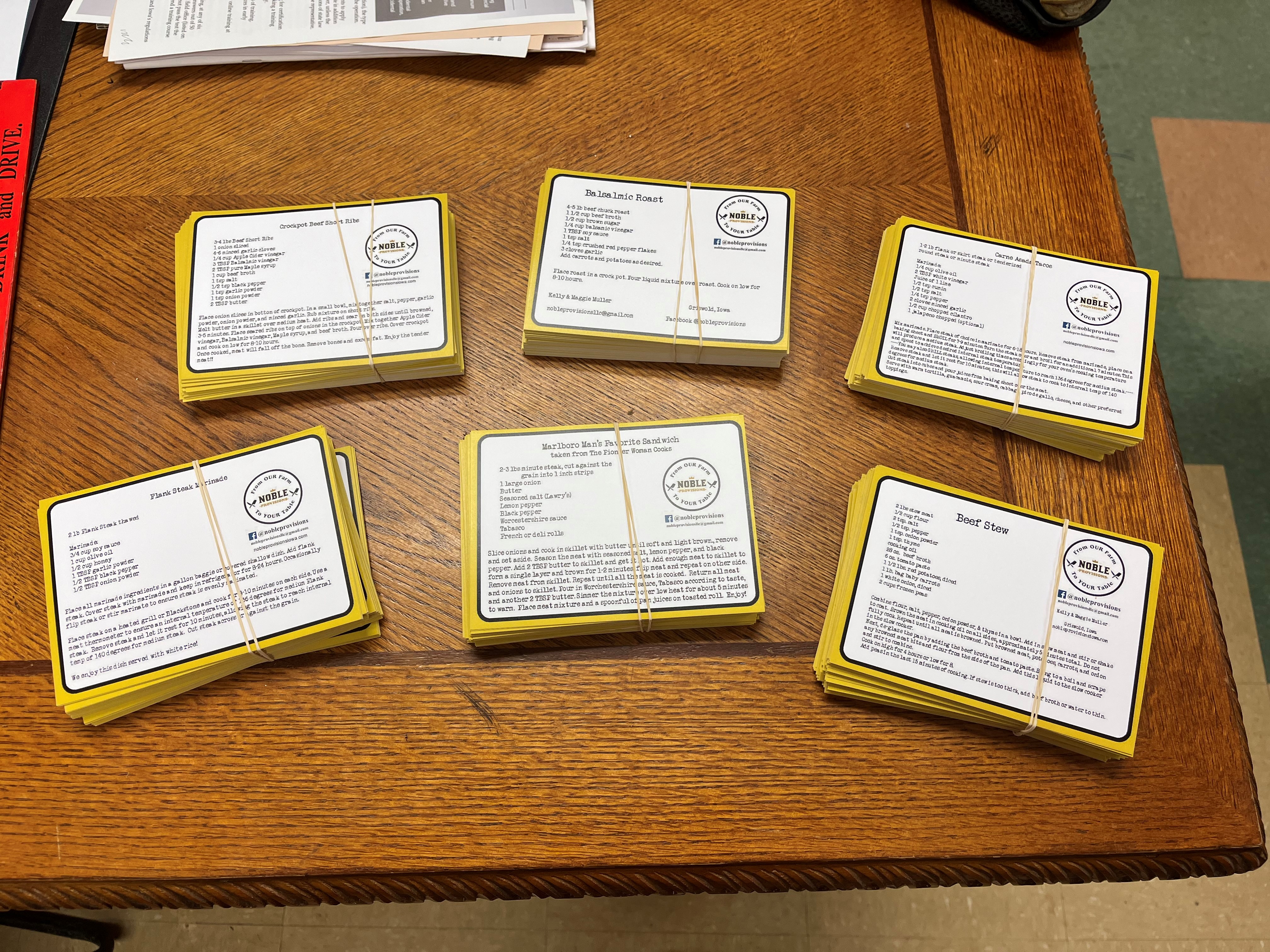 Six piles of recipe cards are ready for their packages.