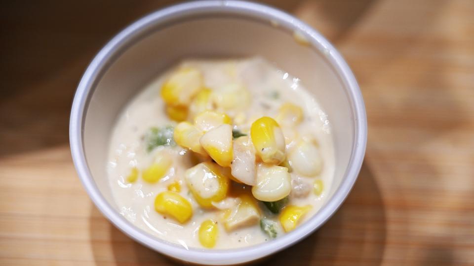 A small dish of creamed corn is served in a small plastic container.