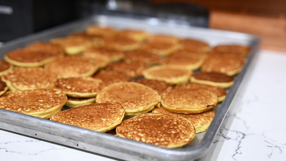 A sheet pan of small corn pancakes sits ready for toppings.