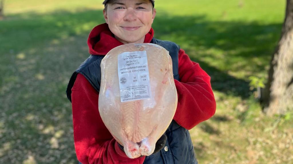 A women holding a large frozen chicken