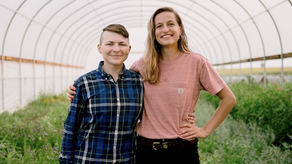 Two farmers standing in their high tunnel 