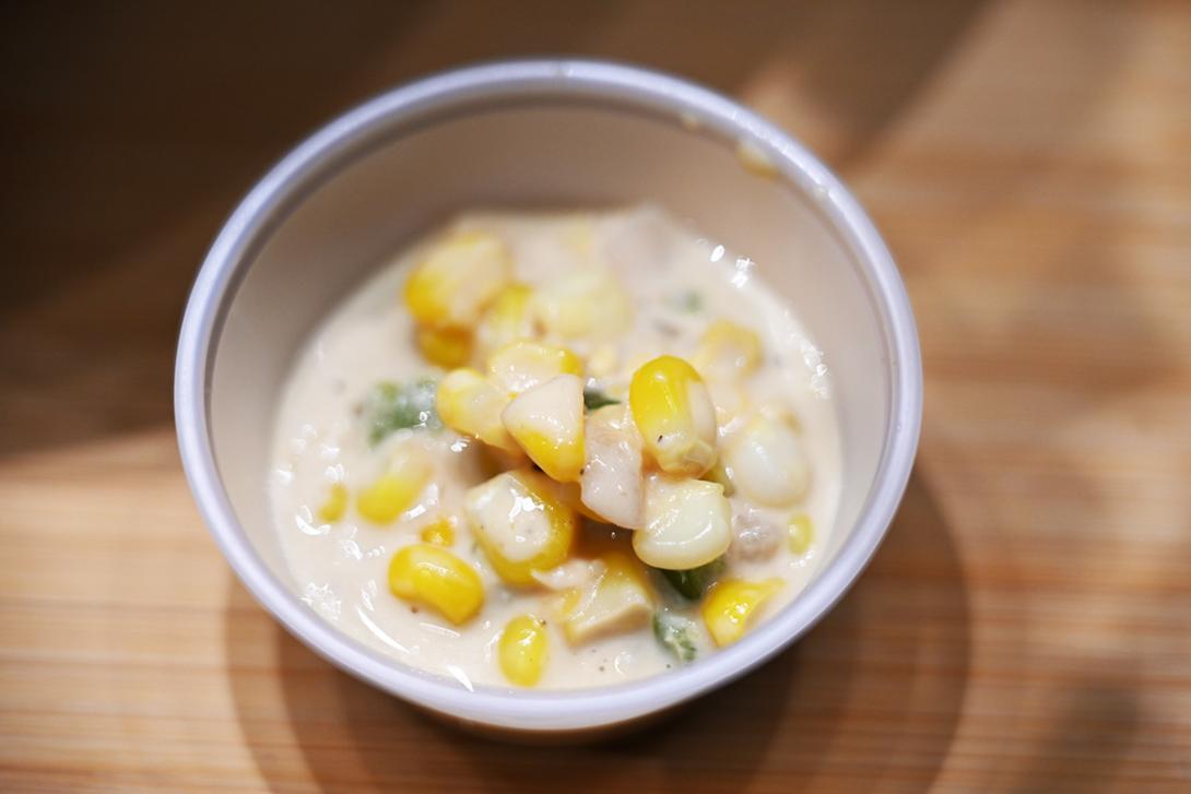 A small dish of creamed corn is served in a small plastic container.