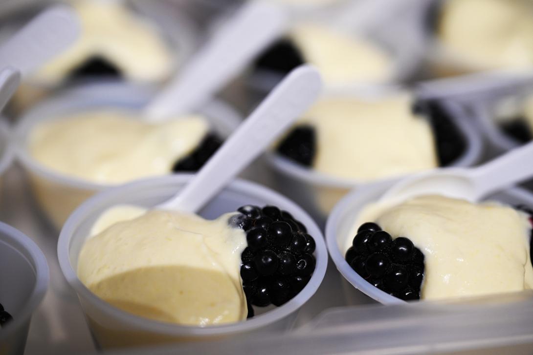 Small servings of cream colored chantilly are served with a little spoon and a blackberry.