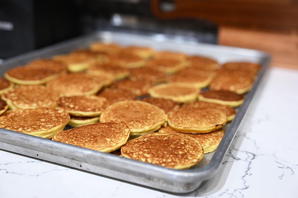 A sheet pan of small corn pancakes sits ready for toppings.